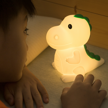 Child admiring dinosaur night light whilst it is glowing and illuminating in their bedroom.