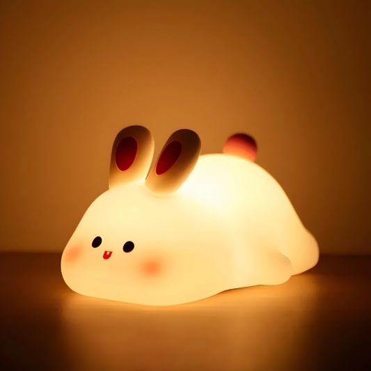 A glowing rabbit-shaped night light casts a soft, warm light in a dark room.